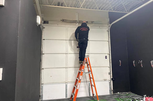 one of our technicials on a ladder installing a commercial garage door