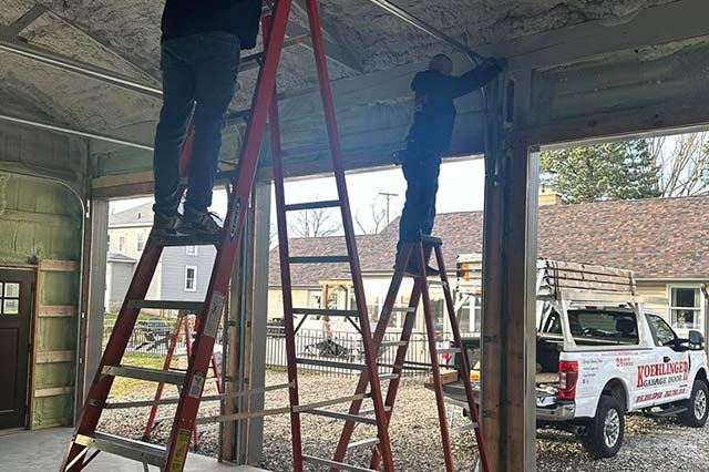 Our techs on ladders installing a garage door