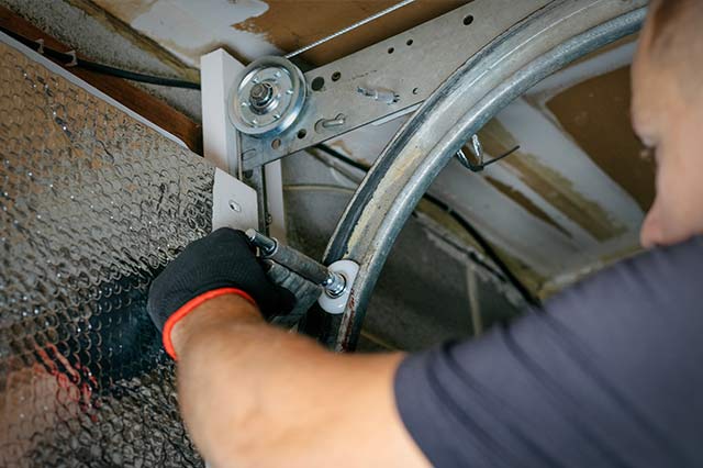 maintenance-home Close up of our tech performing maintenance on a garage door roller and track